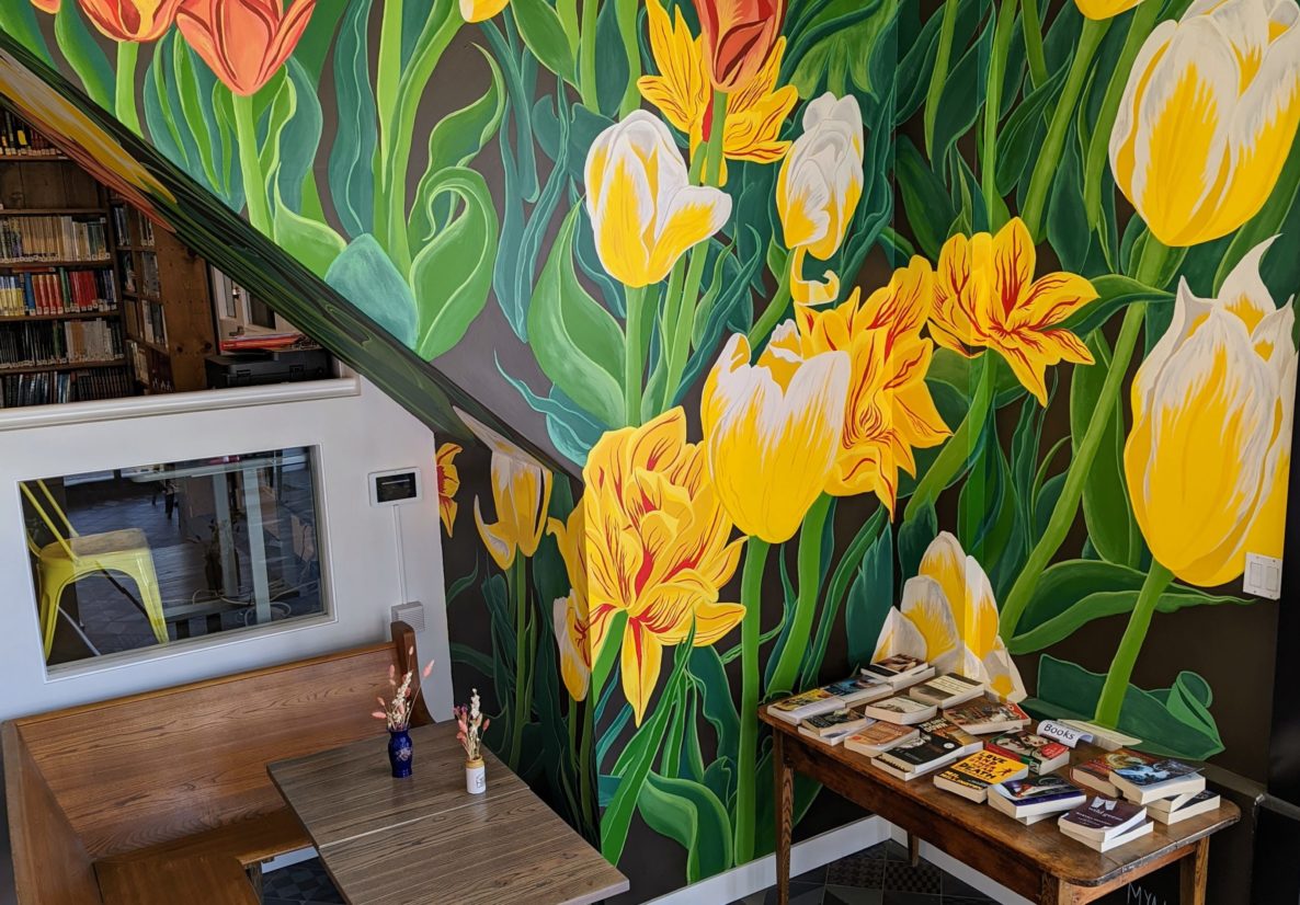 Photo of bright yellow and orange tulip mural in the entry area of Haven painted by Carleton Alumni Mya Duguay